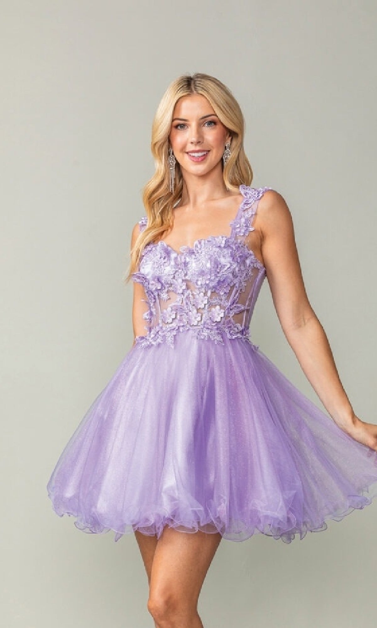 Woman wearing a short lilac dress with floral embellishments on a plain background